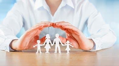 Mains protégeant une figurine représentant une famille